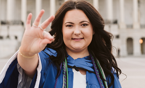 LCU female student in regalia with chap hand sign