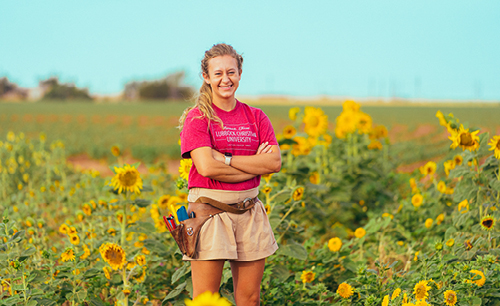 Skyler Richardson standing in a field of sun flowers