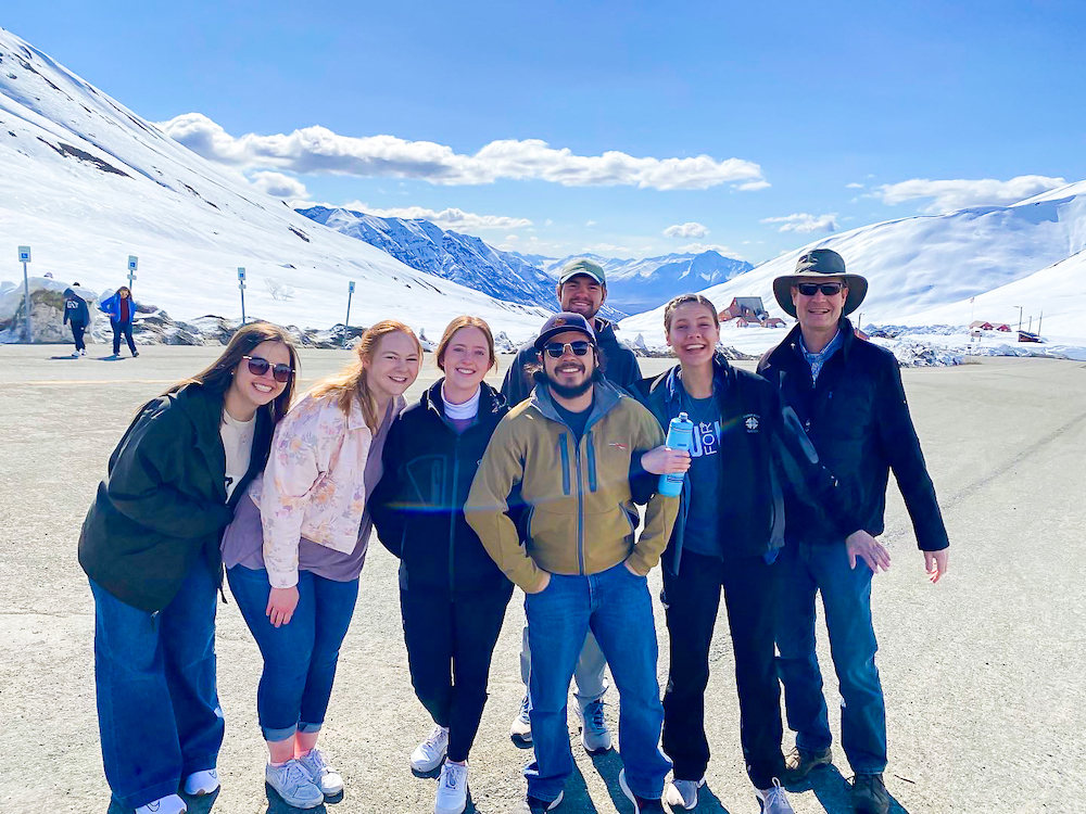 A group of students stands on the tarmac in Alaska