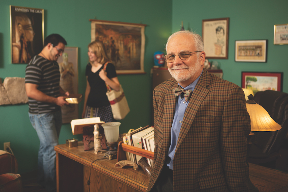 Dr. Jesse Long smiles in front of his desk