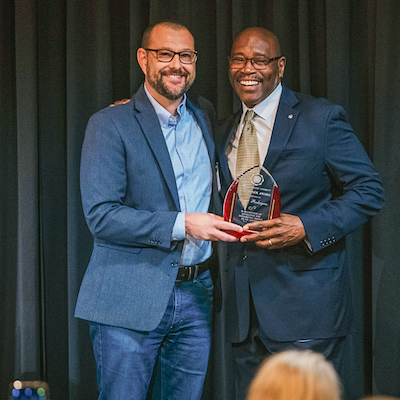 Dr. Jeff Cary presenting George Pendergrass with an award on stage.