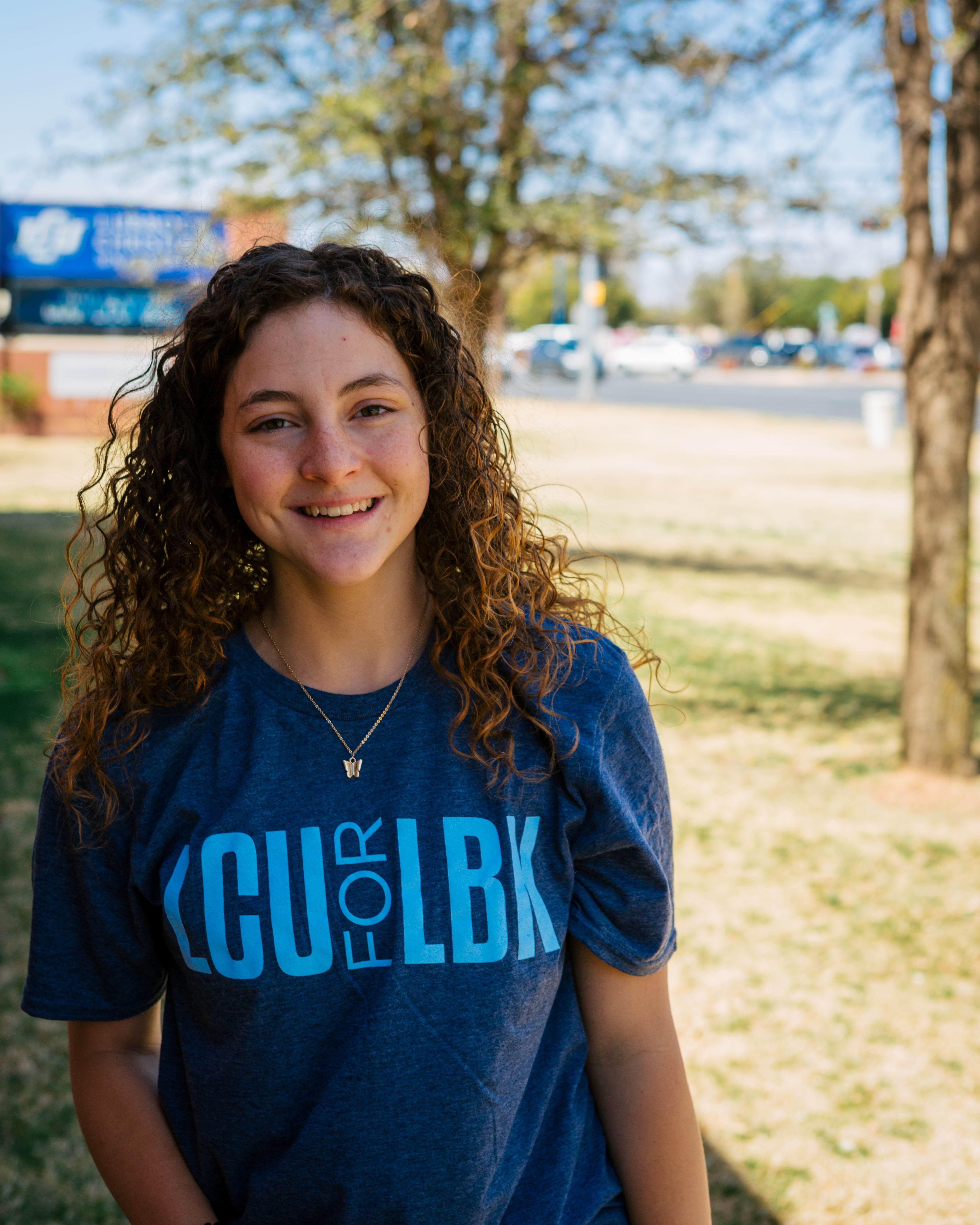 young woman in LCU for LBK shirt smiling on the lawn in front of LCU