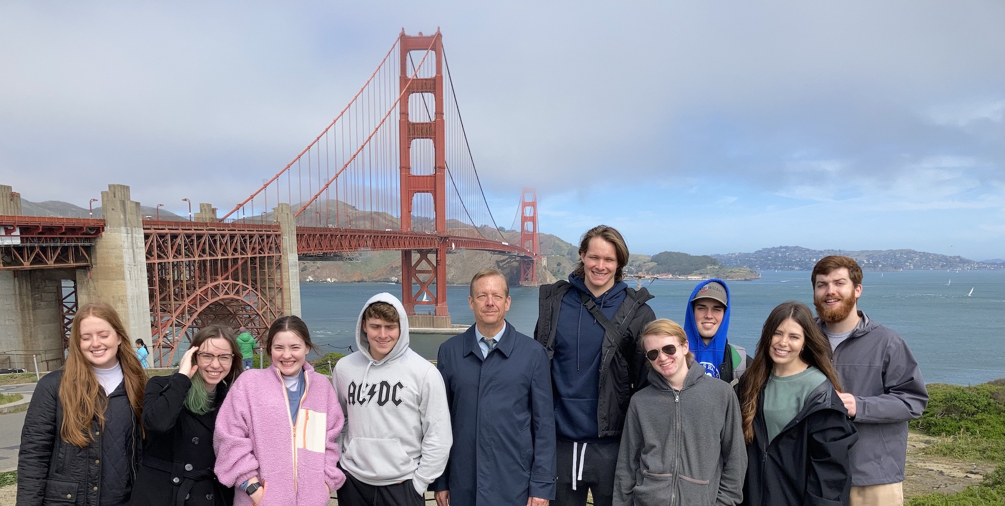 line of students and professor in front of the Golden Gate Bridge