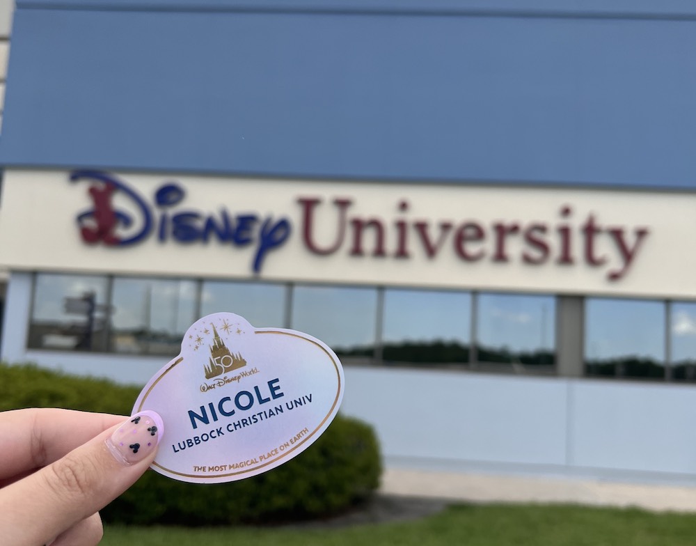 Nicole's Disney World name tag in front of the Disney University building