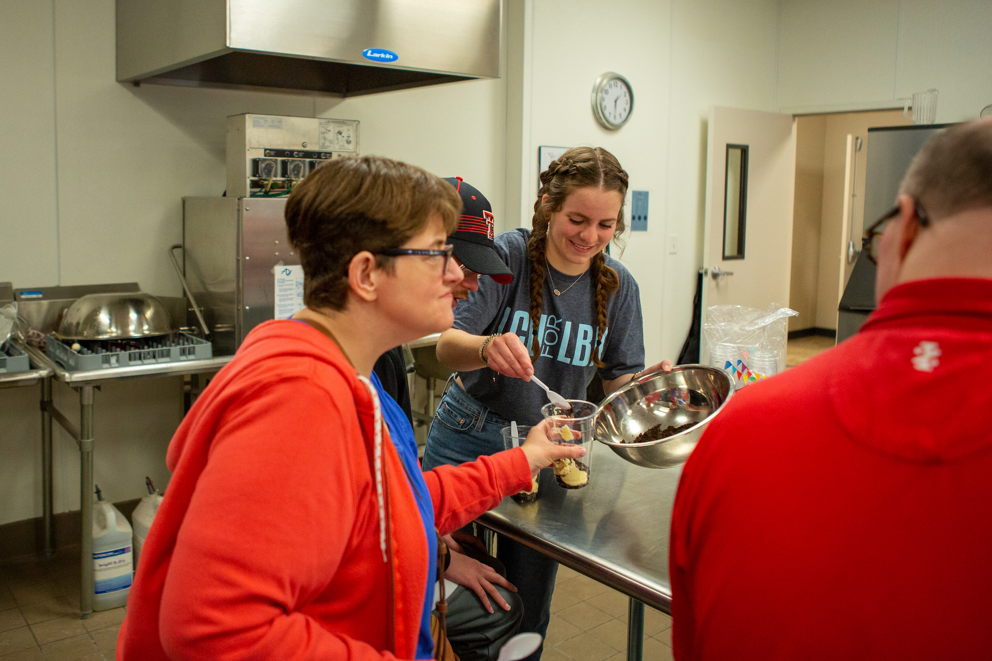 young woman wearing LCU for LBK shirt serving ice cream treats to villagers at High Point Village