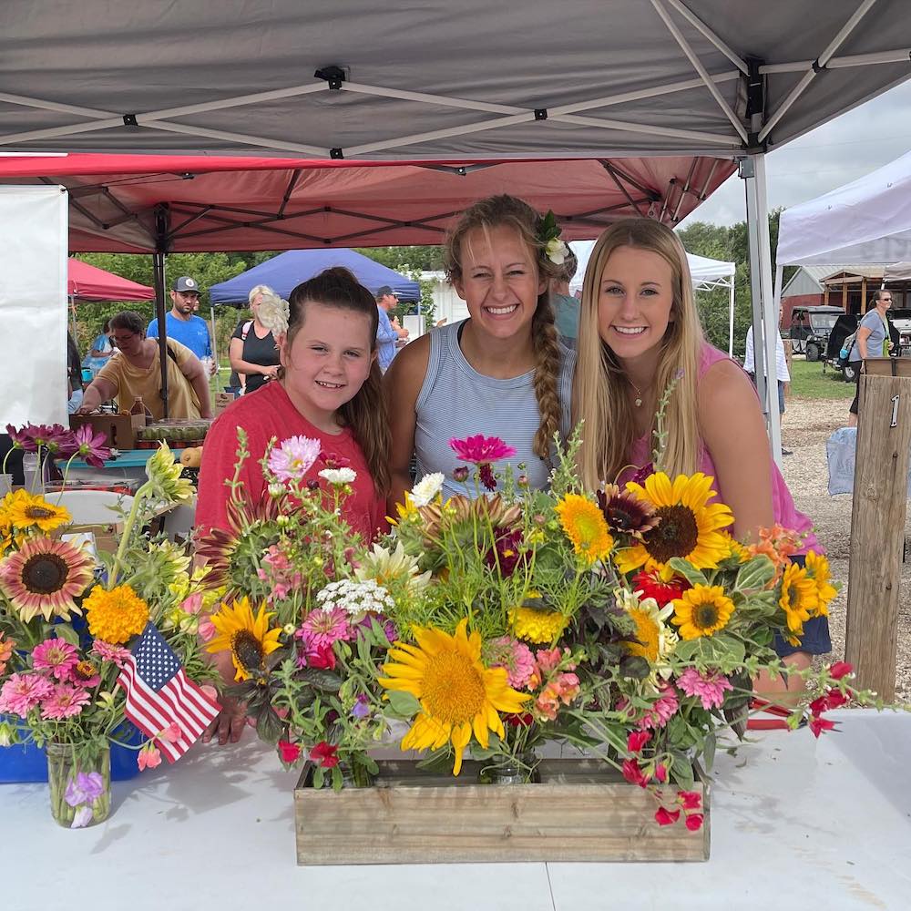 Skyler and her sisters set up a flower booth at a local farmer's market