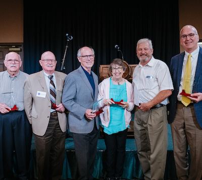 Six members of the Stewart family smile as they receive their award in front of the stage.