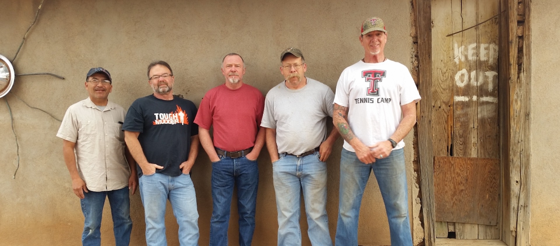 5 men standing in front of a old western building