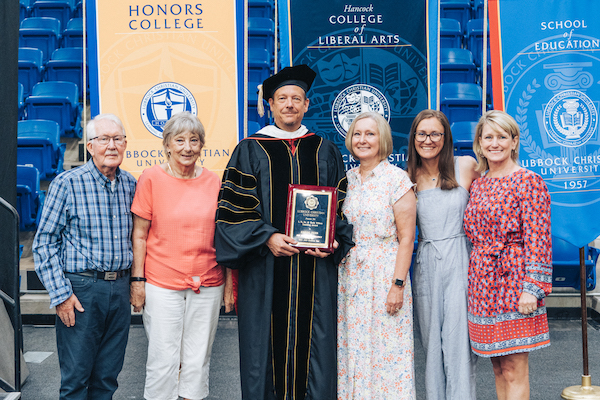 Dr. Kregg Fehr standing with his family and award 