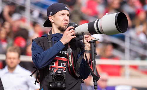 John Moore in photography gear at a Texas Tech game