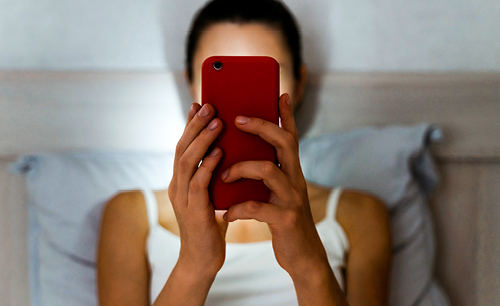 Female in bed looking at a cell phone