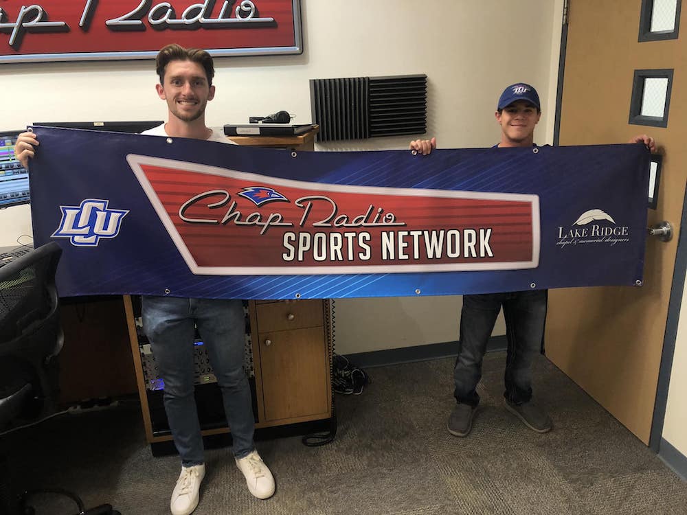 Brennan Riker and Nathan Karseno hold up a Chap Radio Sports Network banner