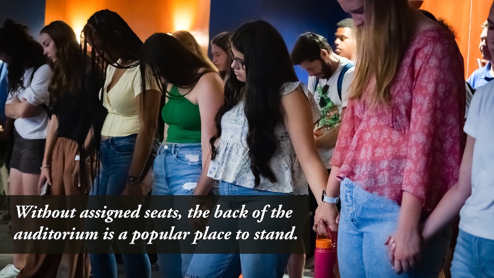 students standing during chapel at the back of the auditorium