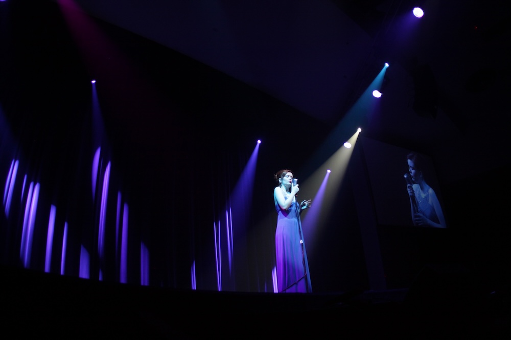 2012 hostess under mood lighting in purple dress singing between acts