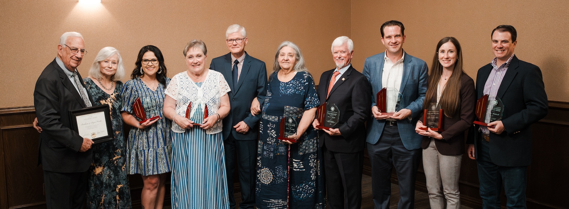 All 10 alumni awardees posing with their awards in the baker conference center