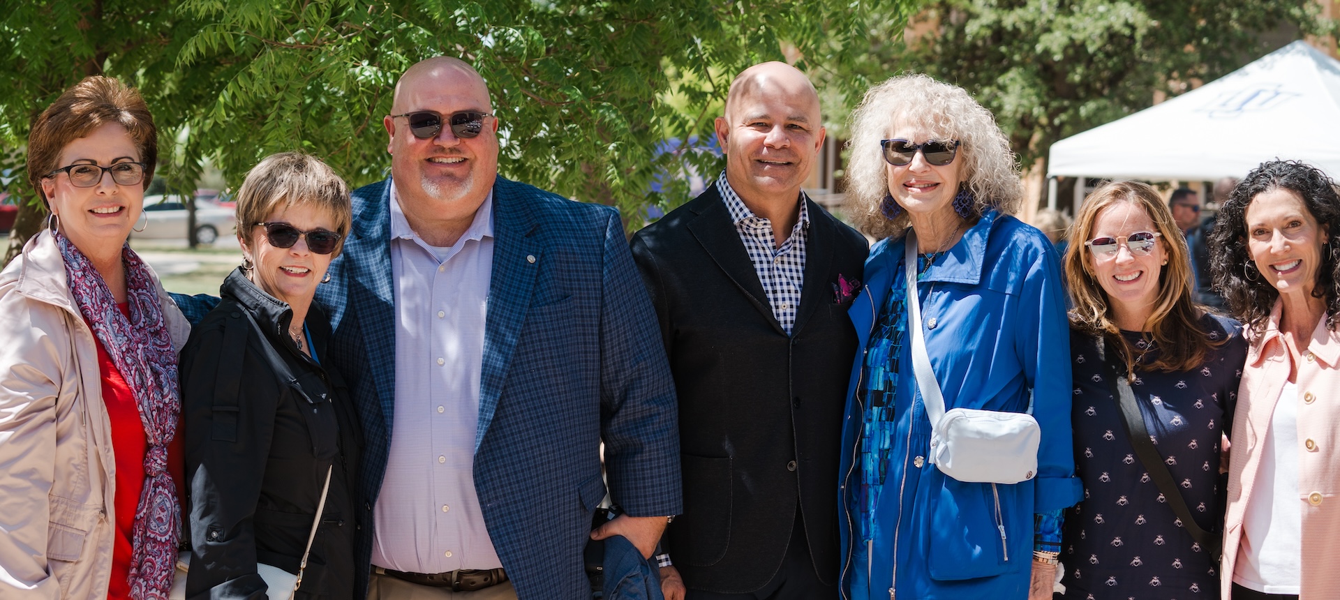 Several local lcu community partners posing in a line at an outside lunch event