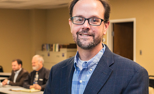 Dr. Mark Sneed smiling for camera in meeting room