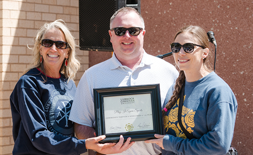 Brian and Marissa Melakian form Play It Again Sports accepting a framed award for being community newcomer  