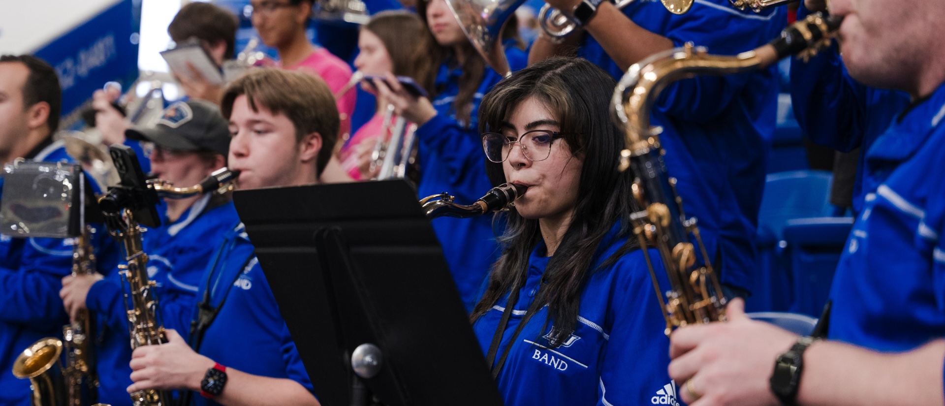 A group of band students in matching blue shirts performing.