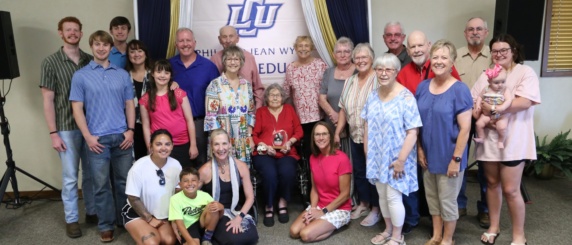 The Wynn Family standing in-front of the presentation of the new college name