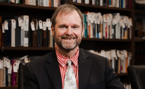 Mark Sneed sitting in-front of a bookshelf
