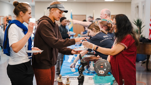 2 students being served in a line of variety of foods