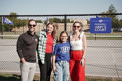 Family standing in from on pickle ball court named Abbies court