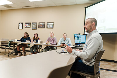 Jeff talking with students around a table in a classroom