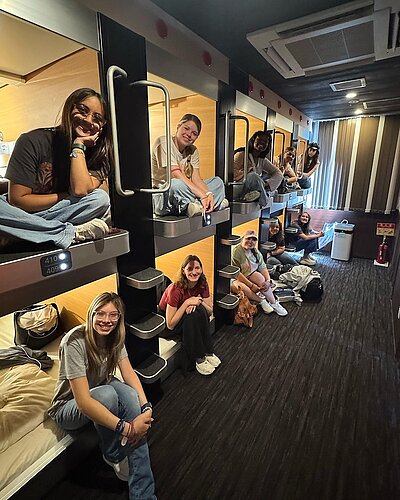 8 students looking out of sleeping pods in Japan