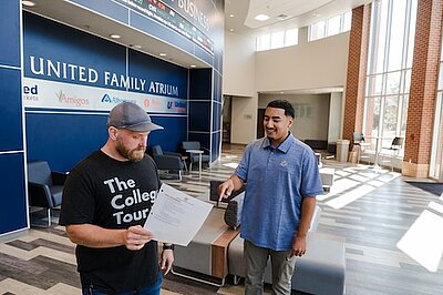 Student going over a script with the camera crew in the business building