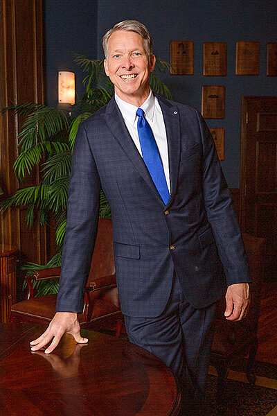 President McDowell posing in the baker entry way, standing with hand on a table