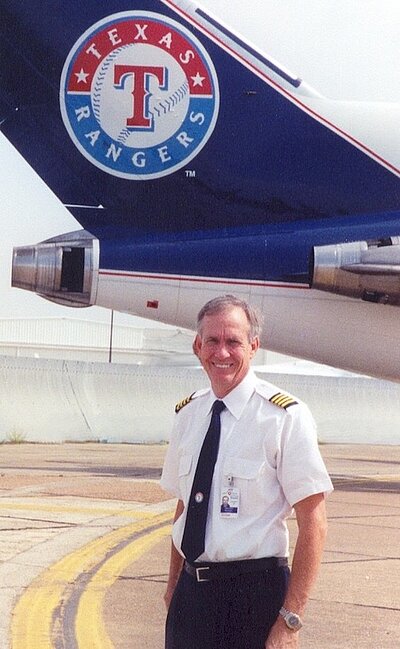 tim on the tarmac with the tail of an airplane with the Texas ranger baseball team logo