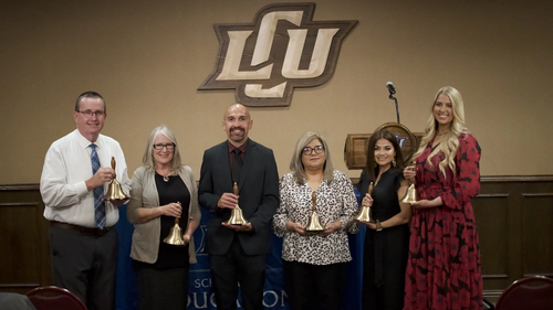 6 educators receiving an award bell at the front of a stage