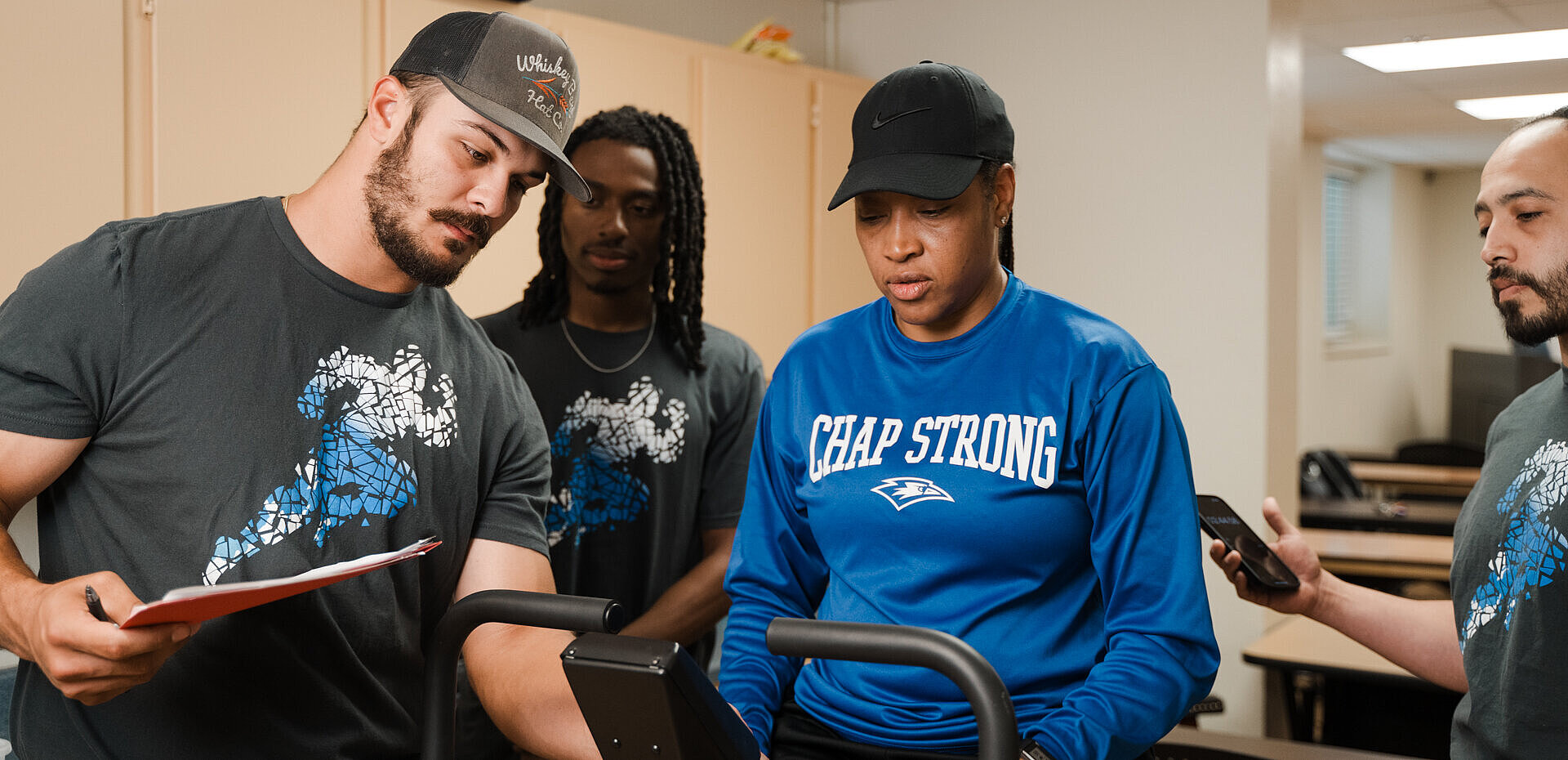 Dr. Monica Hill exercises on a treadmill while three trainers observe, take notes, and time her performance.