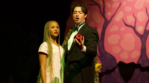 Two actors on stage with holding an apple