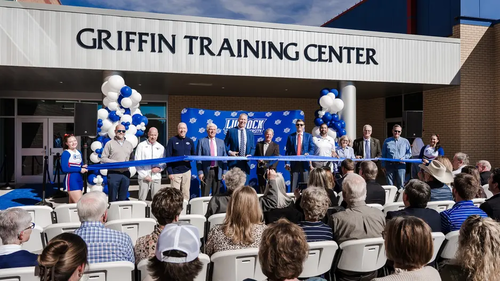 LCU staff cutting a blue ribbon in front of the Griffin Training Center for a crowd of gathered supporters