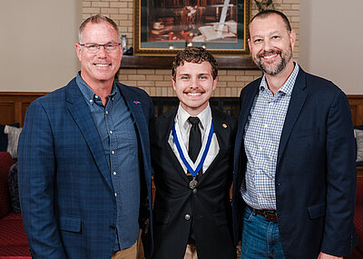 Cameron with a medal around his neck standing with David Fraze and Jeff Cary