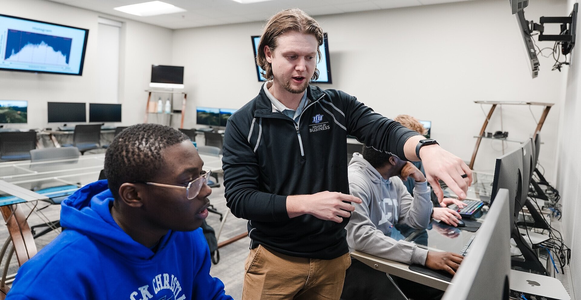 Nathan Richardson (’14) instructs students at a computer while others work in the background.