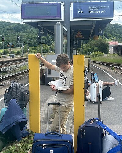 Student reading a book while waiting at a germany train stop