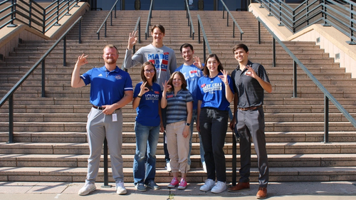 7 LCU graduates throwing the chap sign on outside steps