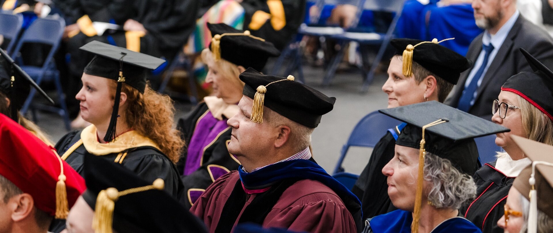 Drs. Laughlin and Richardson sitting with faculty at graduation