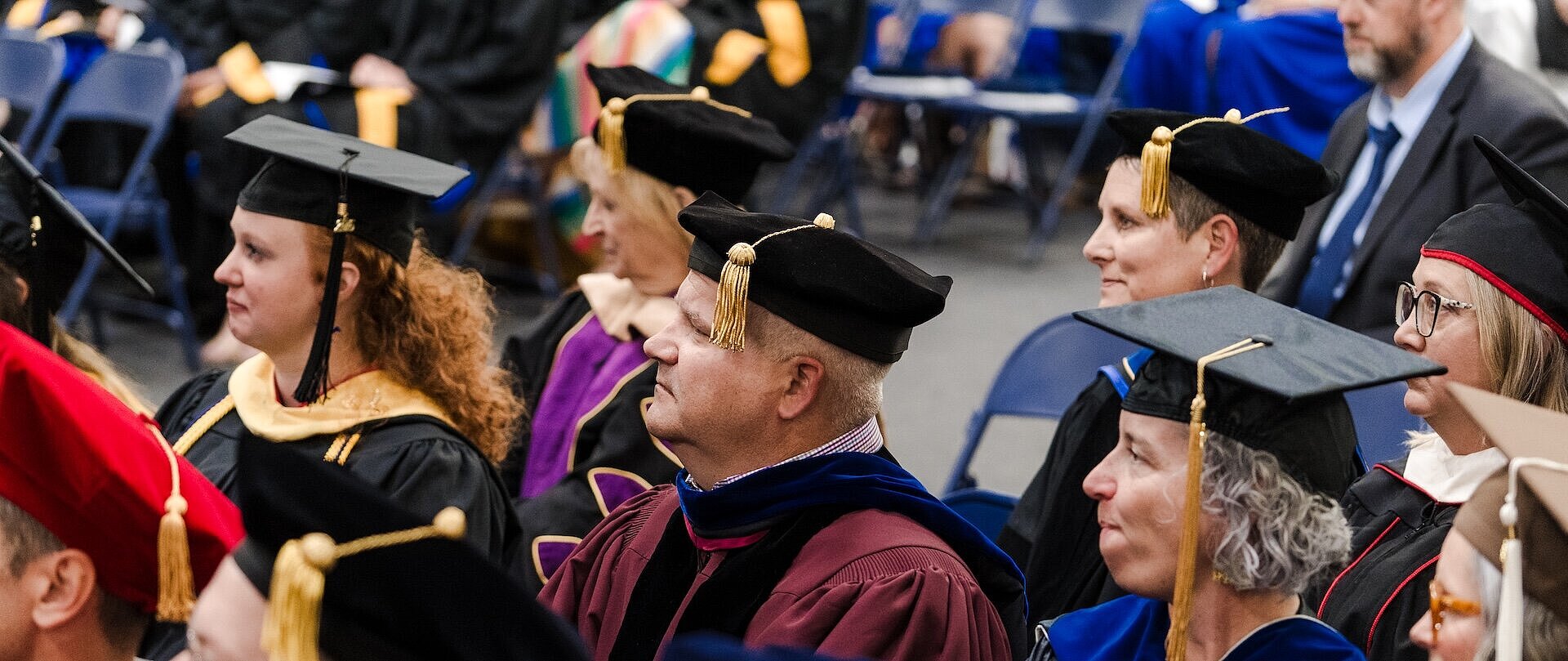 Drs. Laughlin and Richardson sitting with faculty at graduation