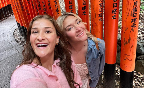 two girls in front of a asian sculpture