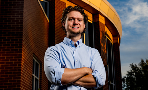Nathan Richardson standing with arms crossed with LCU's business building behind him