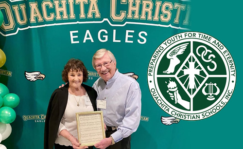 Peggy holding the alma mater, in front of a banner backdrop