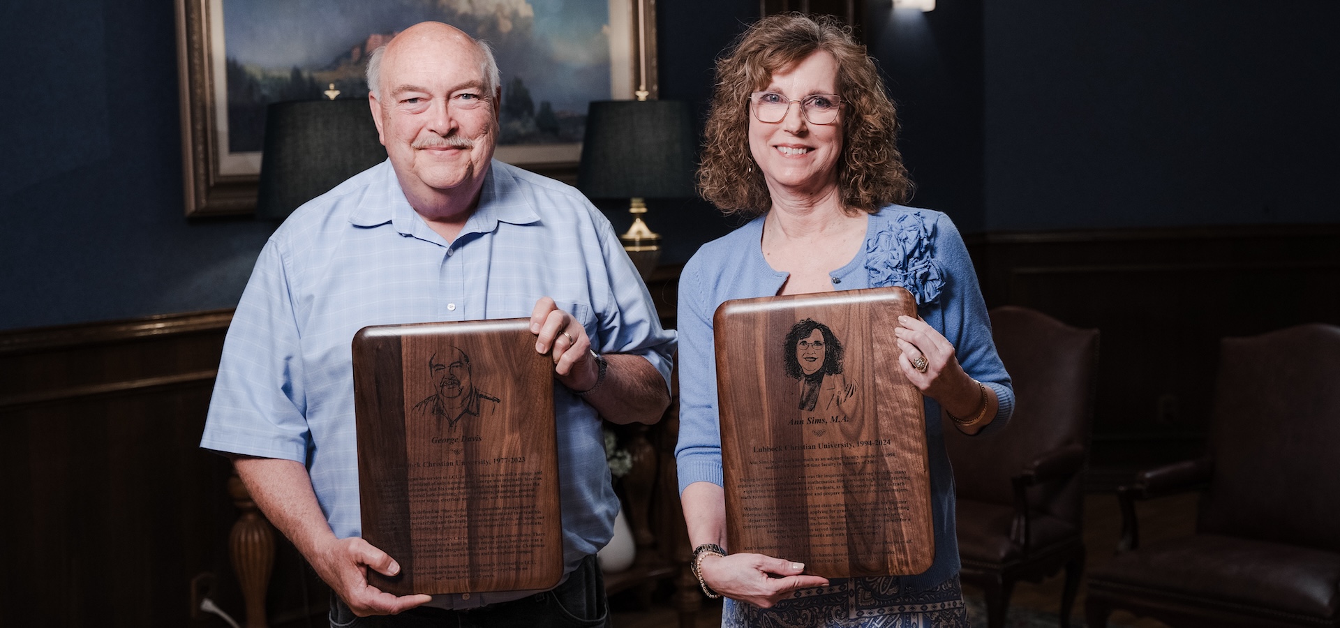 George Davis and Ann Sims posing with their retirement plaques 