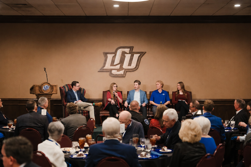 Photograph of the Student Investment Group sitting on stage at a dinner event
