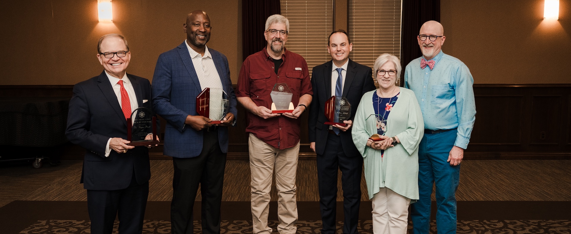 6 Alumni award winners standing with their awards in the baker conference center