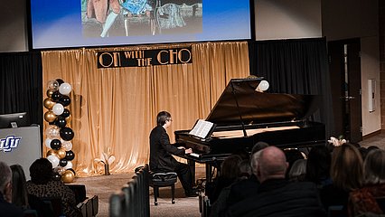 Maestro David Cho playing the piano on stage during the event