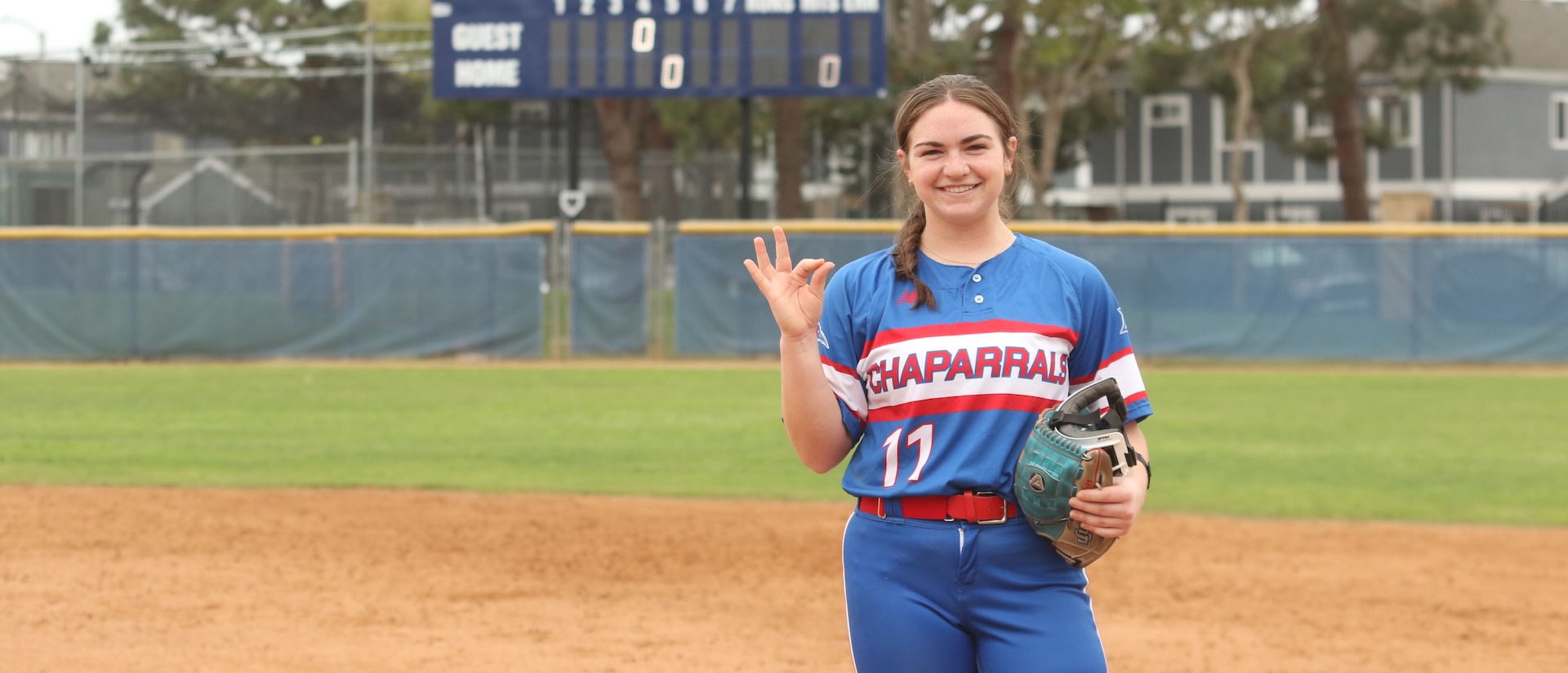 Natalee standing on softball field giving the chap hand sign